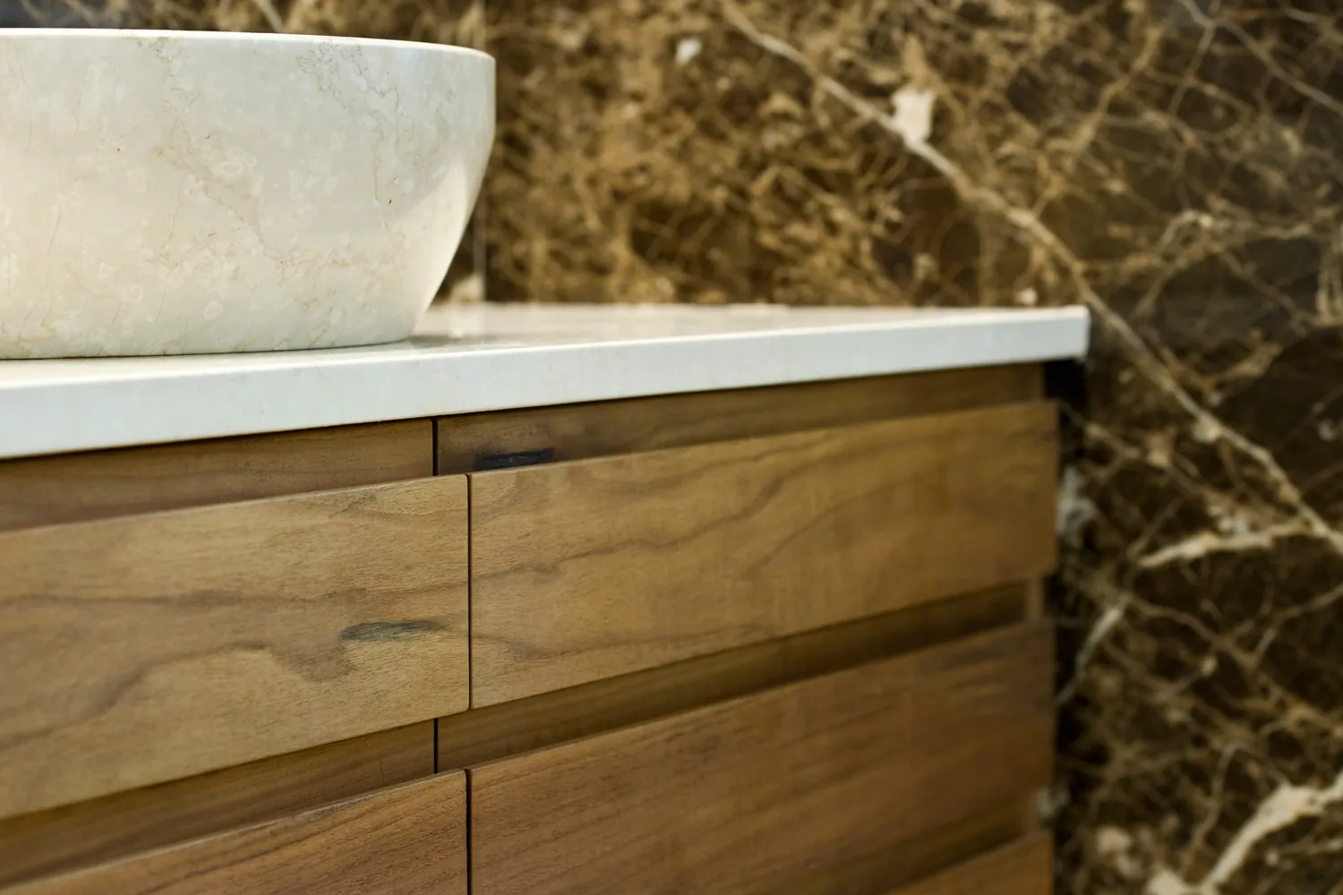 Lavabo in pietra su mobile in legno, davanti al marmo scuro