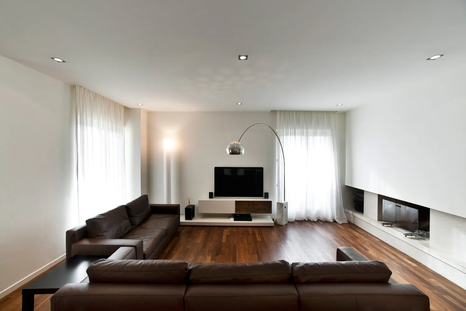 Riqualificazione energetica di una villa: il soggiorno con divani in pelle, lampada ad arco e camino lineare