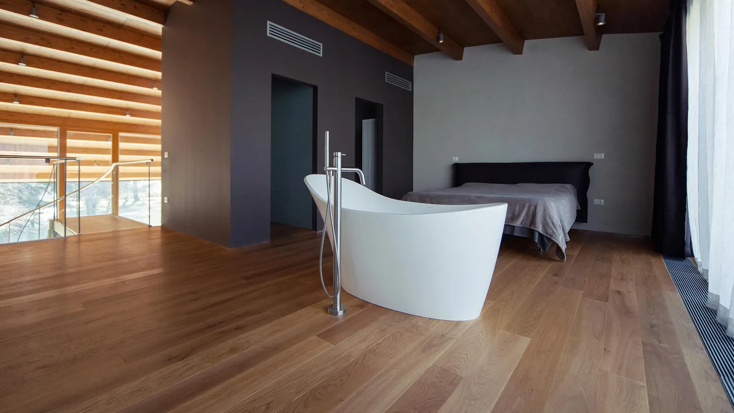 Camera da letto con vasca da bagno libera e soffitto in legno