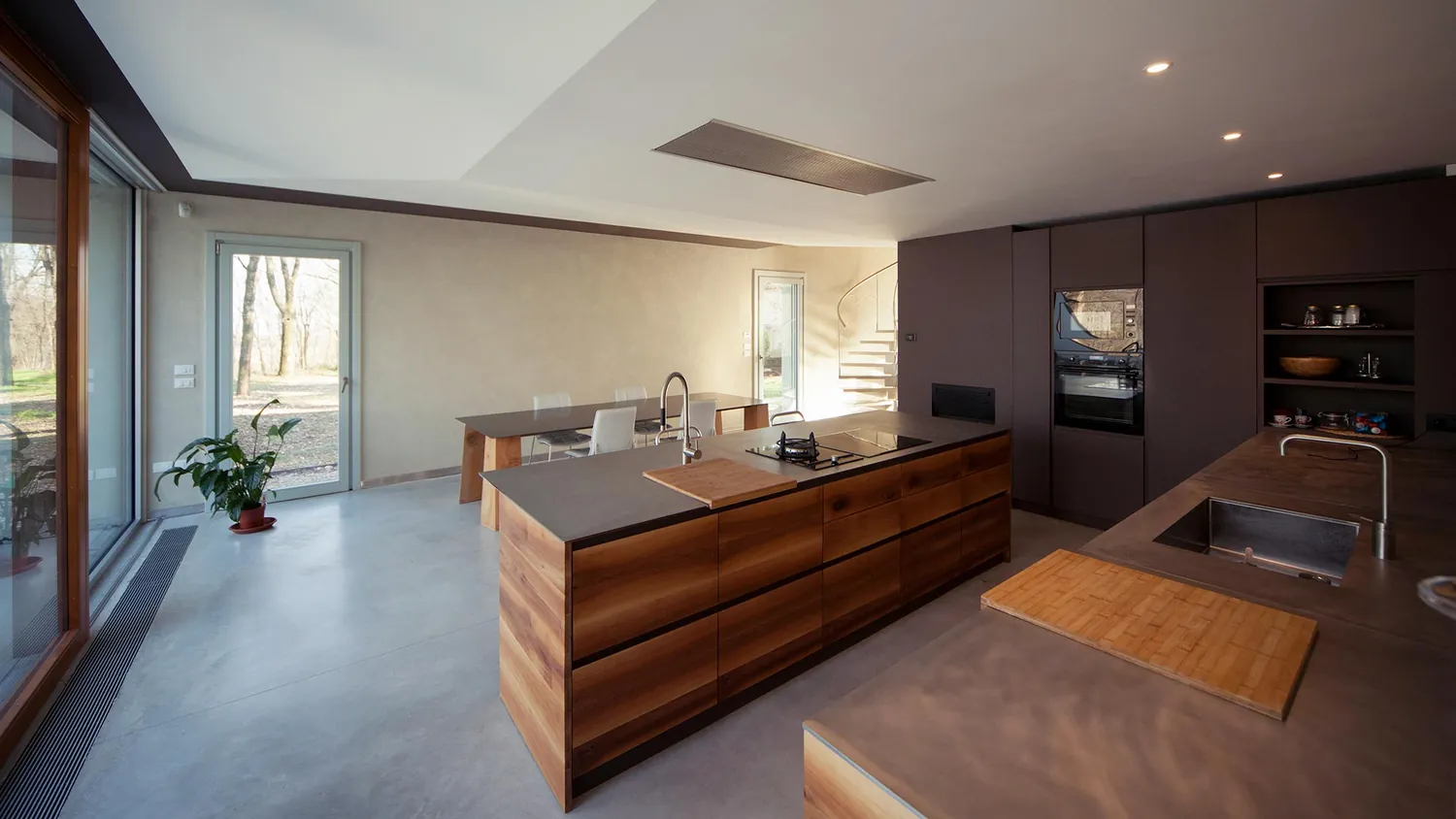 Cucina con isola in legno e piano scuro, aperta sul giardino