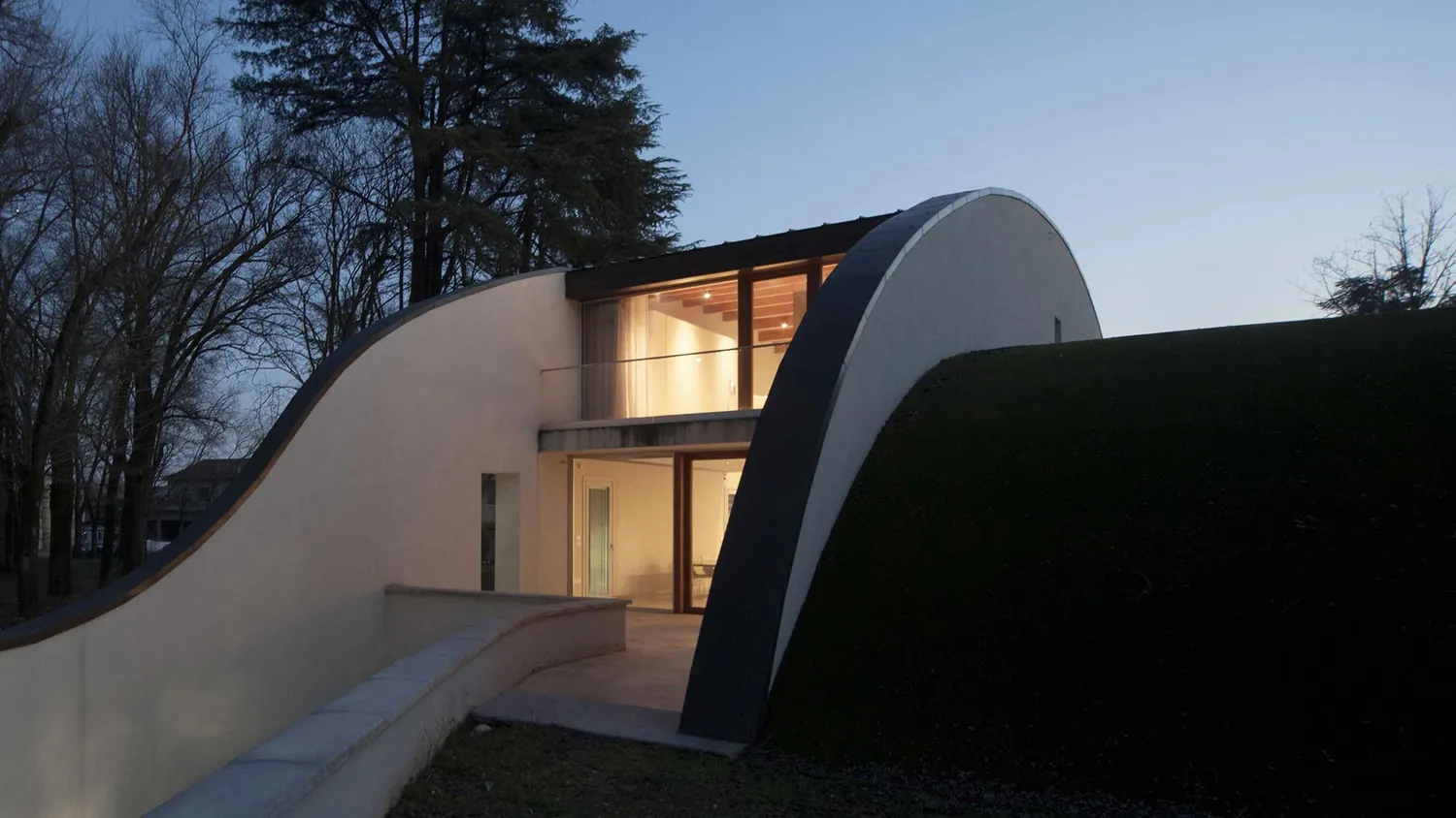 La parete curva e il tetto verde della villa al tramonto