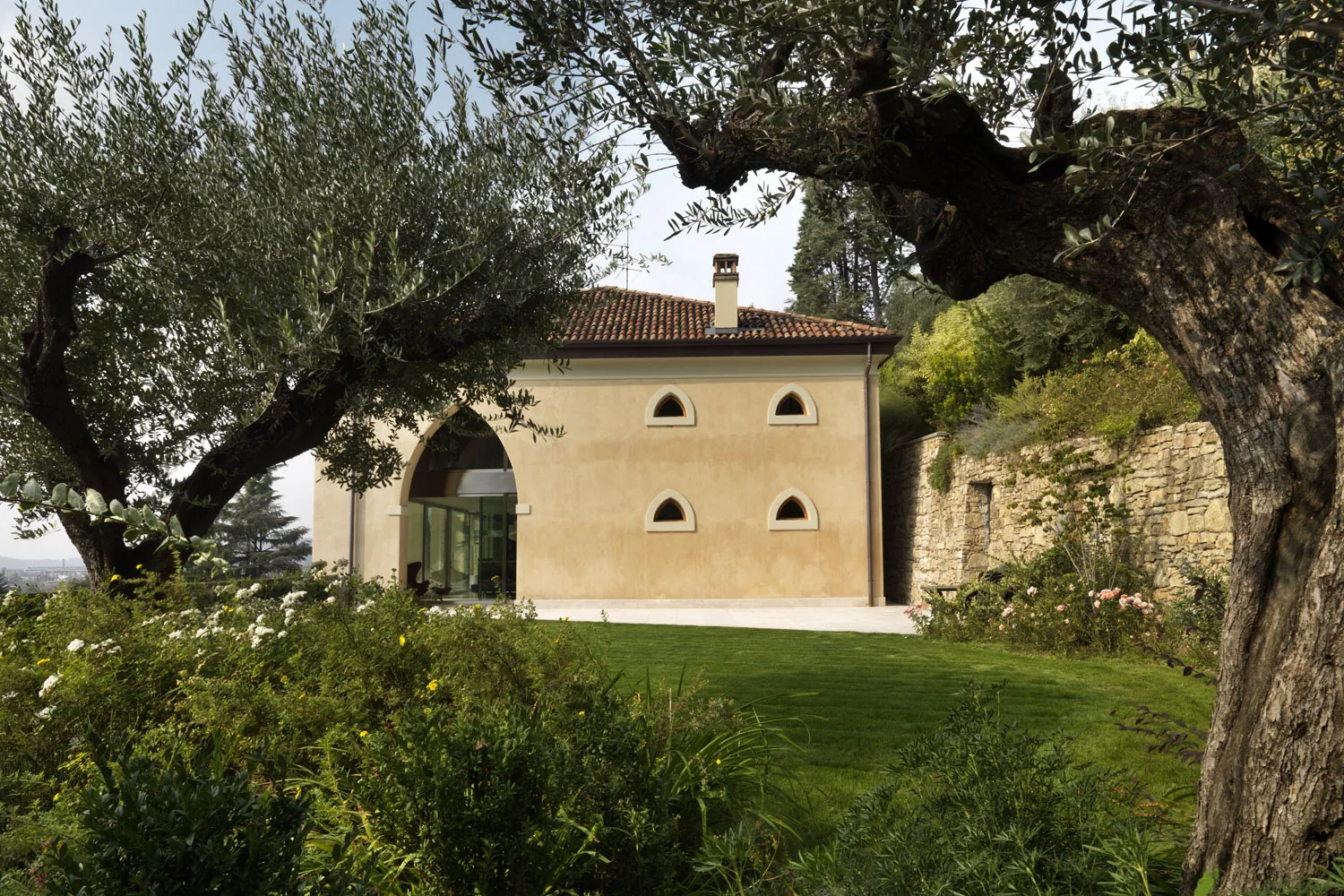 Facciata di una villa storica tra gli ulivi, con il prato curato in primo piano