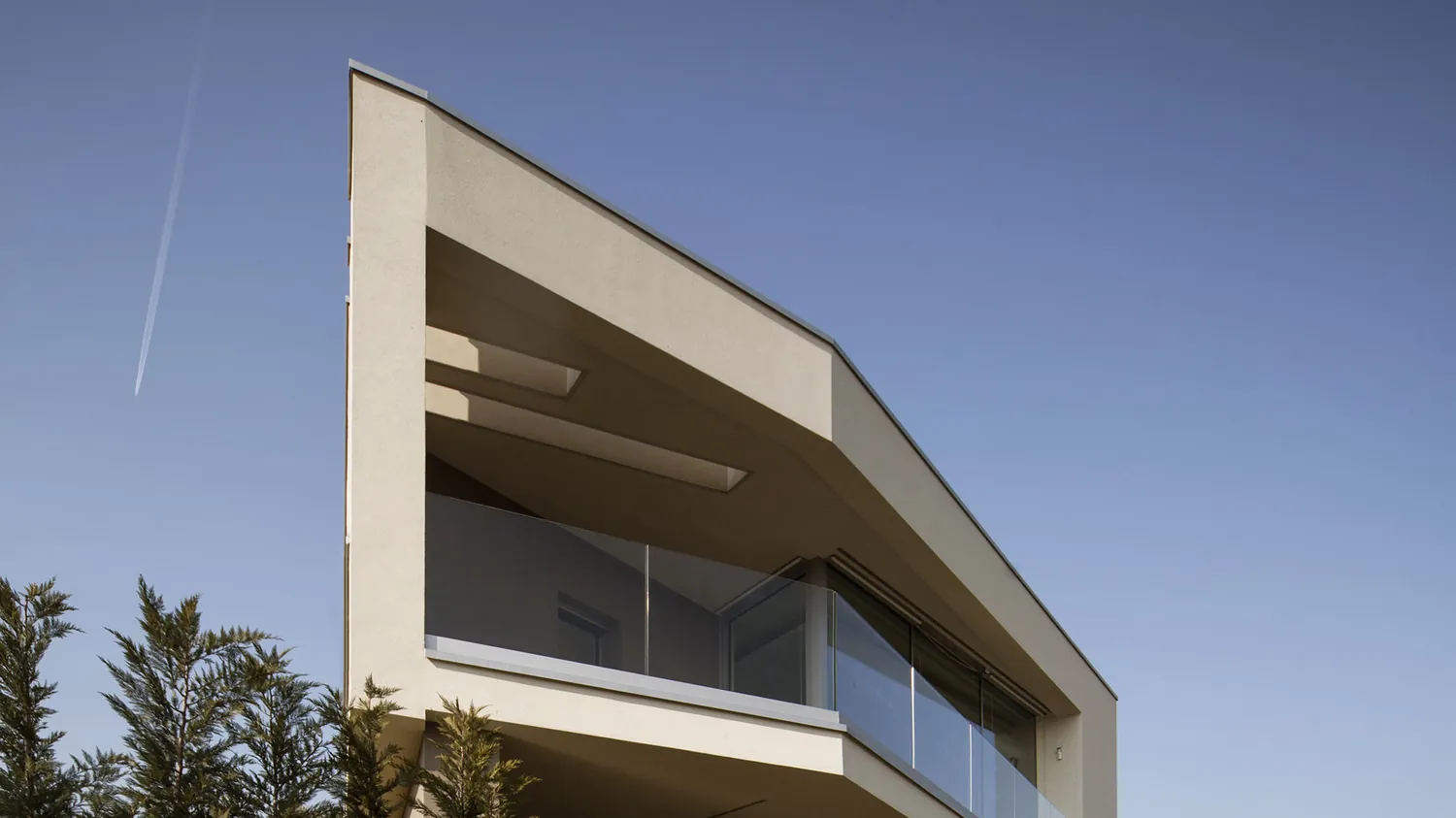 Lo spigolo della villa con la loggia e il parapetto in vetro, contro il cielo blu