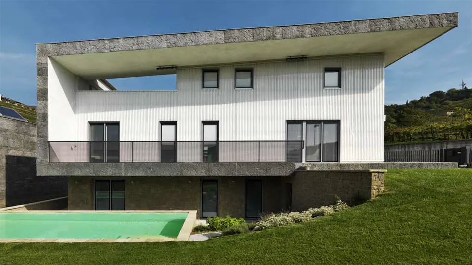 Villa bianca su due livelli con piscina e prato in pendio
