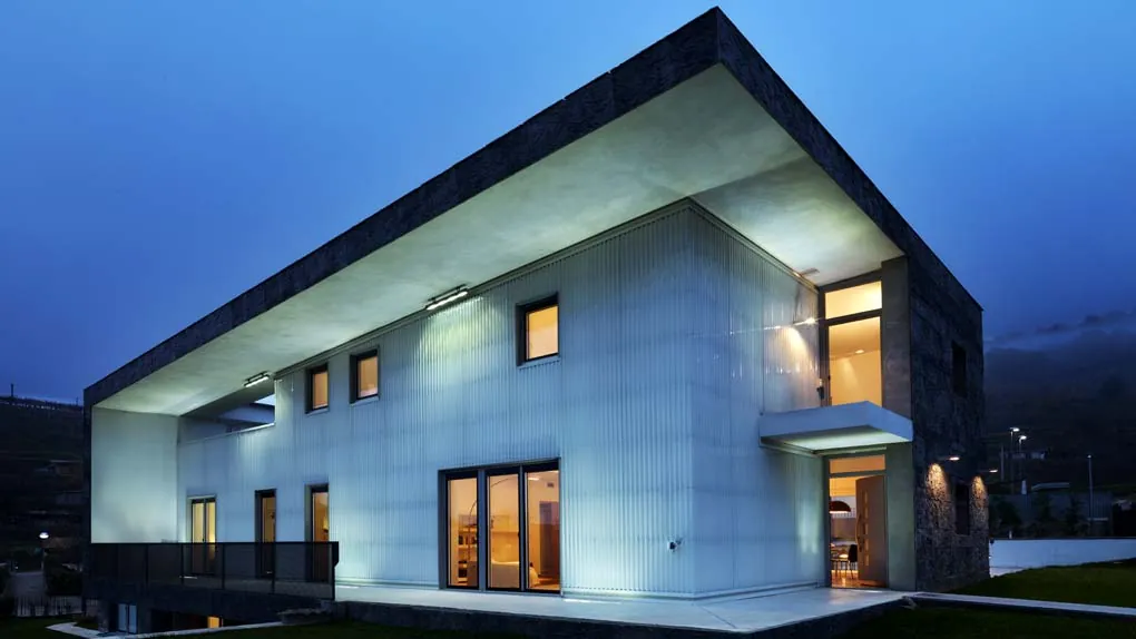 Villa prefabbricata a Gussago al crepuscolo, con la facciata illuminata e il grande tetto a sbalzo