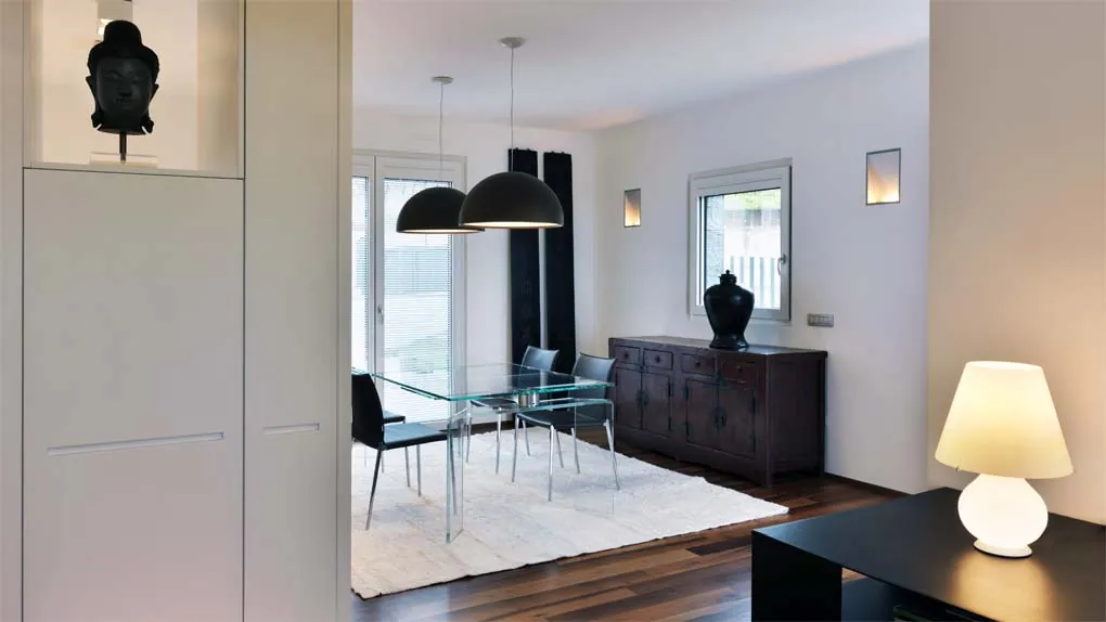 Zona pranzo luminosa con tavolo in vetro e lampade a sospensione