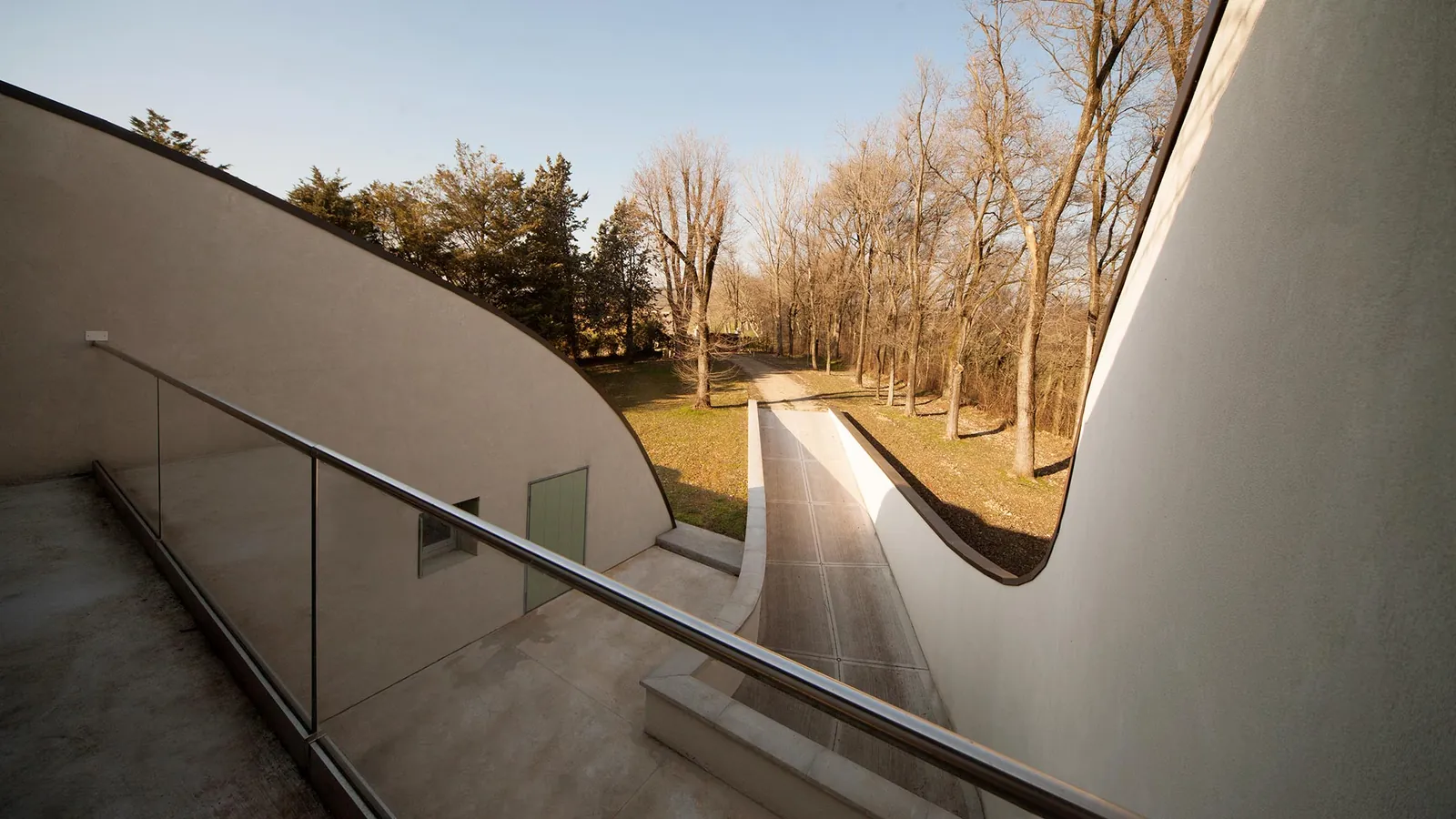 Rampa curva di una villa tra gli alberi delle colline moreniche, al tramonto