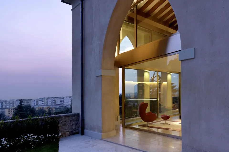 Portico vetrato a doppia altezza di un edificio storico sulle colline di Brescia, al tramonto