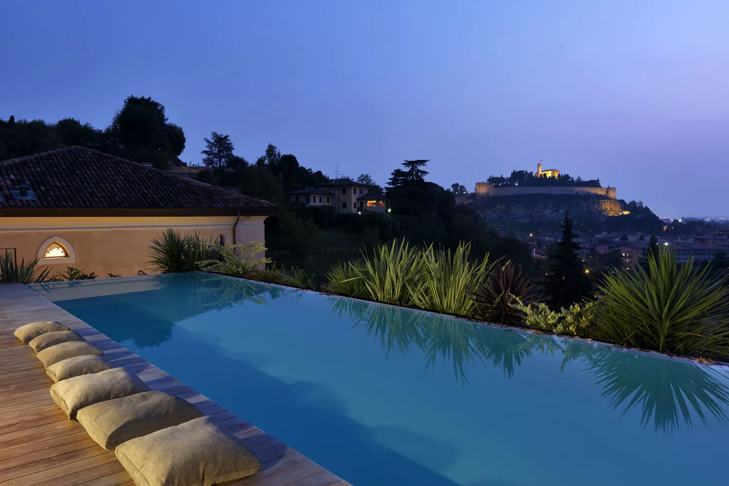 Piscina a sfioro sul panorama della città al crepuscolo, con il castello sulla collina